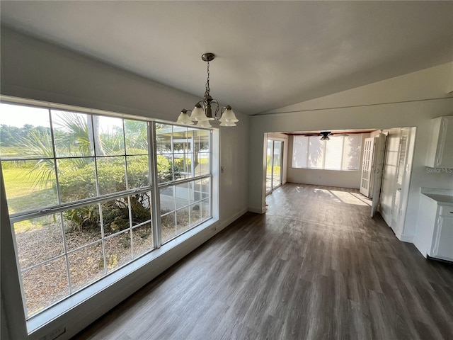 unfurnished dining area featuring a wealth of natural light, dark wood-type flooring, lofted ceiling, and a notable chandelier