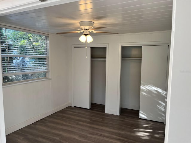 unfurnished bedroom featuring multiple closets, ceiling fan, and dark wood-type flooring