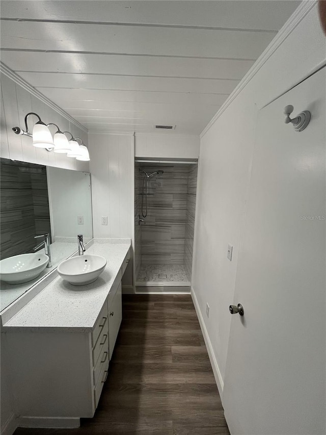 bathroom featuring a tile shower, crown molding, vanity, and hardwood / wood-style flooring