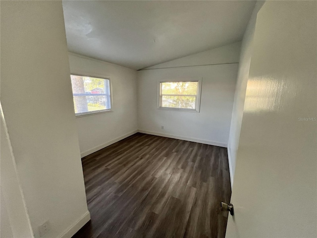 empty room with vaulted ceiling, plenty of natural light, and dark wood-type flooring