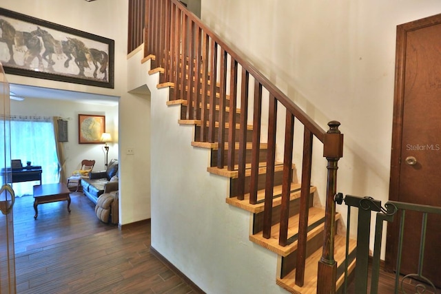 stairs with hardwood / wood-style flooring and a towering ceiling