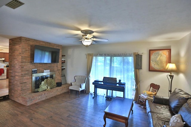 living room with dark wood-type flooring, a fireplace, and ceiling fan