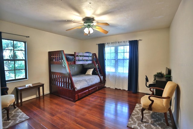 bedroom featuring ceiling fan, multiple windows, and dark hardwood / wood-style flooring