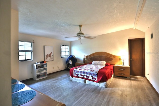 bedroom featuring vaulted ceiling, wood-type flooring, multiple windows, and ceiling fan