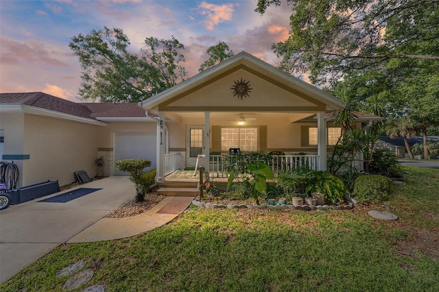 view of front of property featuring covered porch, a yard, and a garage