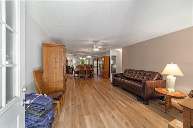 living room with ceiling fan, light hardwood / wood-style flooring, and a textured ceiling