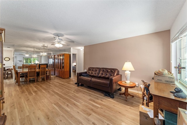 living room featuring ceiling fan, light hardwood / wood-style floors, and a textured ceiling