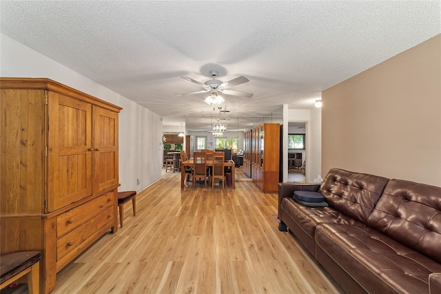 living room with a textured ceiling, light hardwood / wood-style floors, and ceiling fan