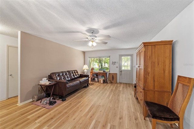 living room featuring ceiling fan, light hardwood / wood-style floors, and a textured ceiling