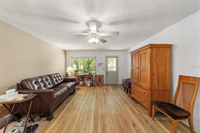 living room featuring a textured ceiling, light wood-type flooring, and ceiling fan