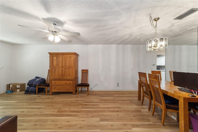 dining space featuring ceiling fan with notable chandelier, light hardwood / wood-style floors, and a textured ceiling