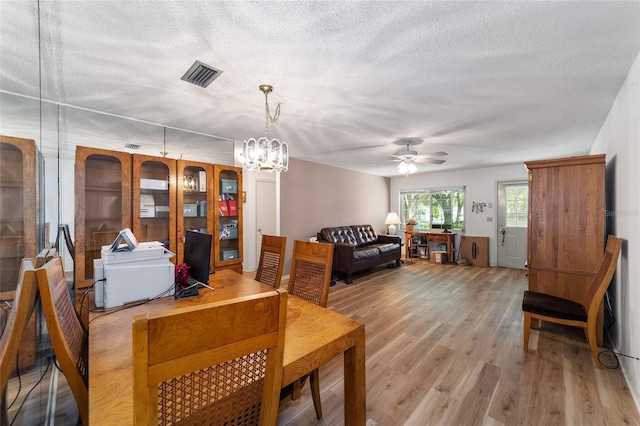 dining room with ceiling fan with notable chandelier, a textured ceiling, and hardwood / wood-style flooring