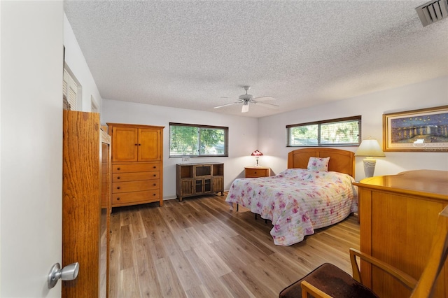 bedroom with ceiling fan, light hardwood / wood-style flooring, and a textured ceiling