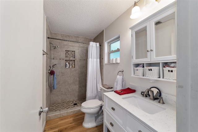 bathroom featuring vanity, hardwood / wood-style flooring, toilet, a textured ceiling, and walk in shower