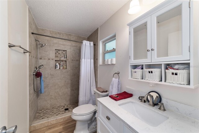 bathroom featuring vanity, wood-type flooring, a textured ceiling, and curtained shower