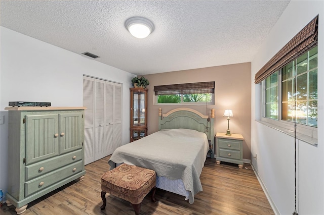 bedroom featuring a closet, light hardwood / wood-style flooring, and a textured ceiling