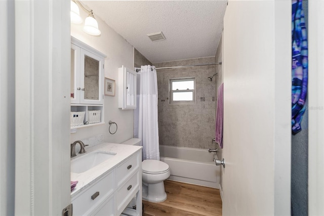 full bathroom featuring vanity, hardwood / wood-style flooring, toilet, shower / bath combo with shower curtain, and a textured ceiling