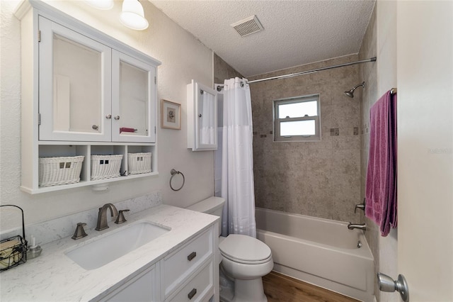 full bathroom featuring vanity, hardwood / wood-style flooring, toilet, a textured ceiling, and shower / tub combo