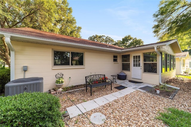 back of house with central air condition unit and a sunroom