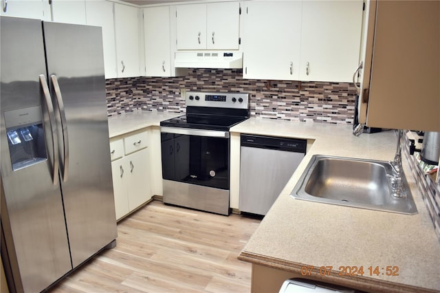 kitchen with sink, light wood-type flooring, tasteful backsplash, white cabinetry, and stainless steel appliances