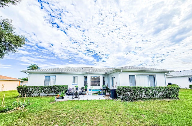 rear view of property with a lawn and a patio