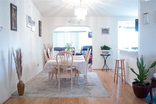 dining area featuring light hardwood / wood-style flooring, a chandelier, and lofted ceiling