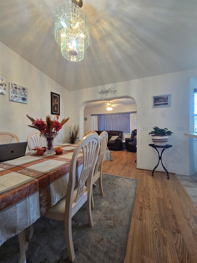 dining space featuring wood-type flooring and ceiling fan with notable chandelier