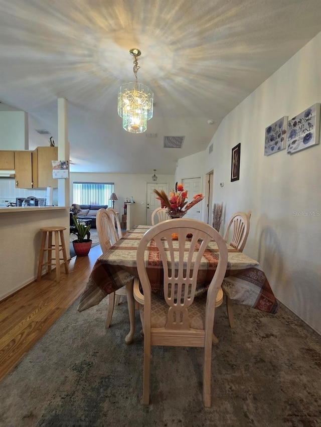 dining room featuring a notable chandelier, dark hardwood / wood-style floors, and vaulted ceiling