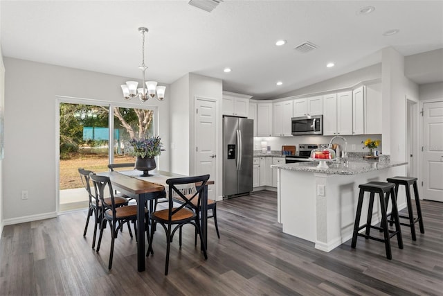 kitchen featuring dark hardwood / wood-style flooring, stainless steel appliances, decorative light fixtures, a chandelier, and white cabinetry