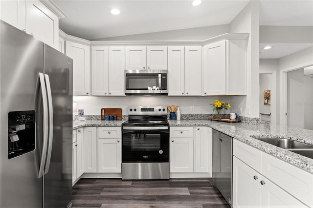 kitchen featuring white cabinets, light stone countertops, appliances with stainless steel finishes, and vaulted ceiling