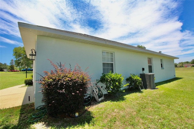 view of side of property featuring a lawn and central AC unit