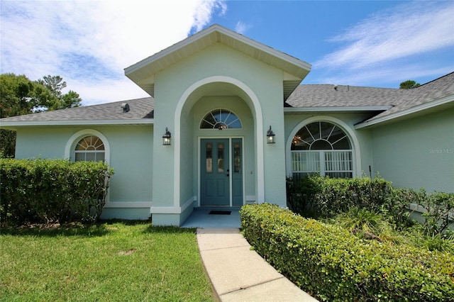 view of exterior entry featuring a lawn