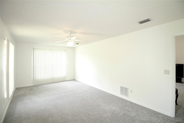 carpeted empty room featuring plenty of natural light, ceiling fan, and a textured ceiling