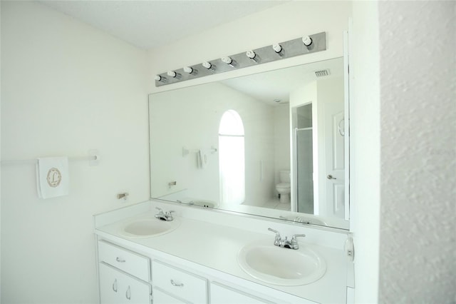 bathroom with double sink, toilet, and vanity with extensive cabinet space