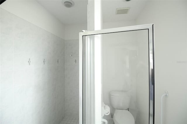 bathroom with a shower with shower door and toilet