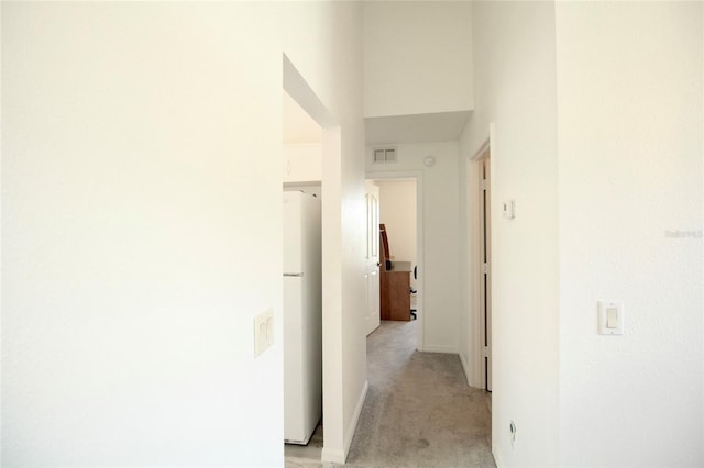 hall featuring carpet and a towering ceiling