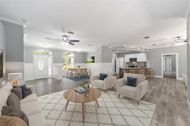 living room featuring crown molding, ceiling fan, and light wood-type flooring