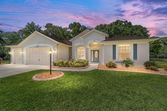 view of front facade with a garage, driveway, a front yard, and stucco siding