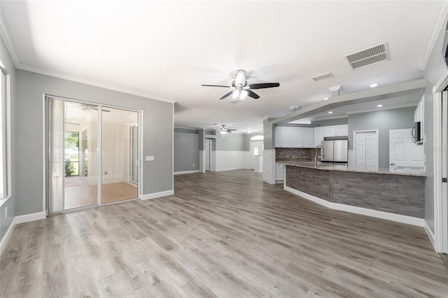 unfurnished living room with visible vents, crown molding, and ceiling fan