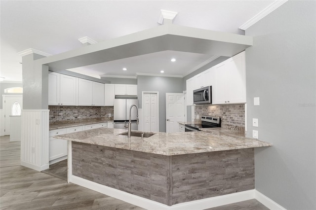 kitchen with light stone counters, a peninsula, stainless steel appliances, white cabinetry, and a sink