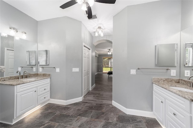 bathroom featuring two vanities, a sink, baseboards, and ceiling fan