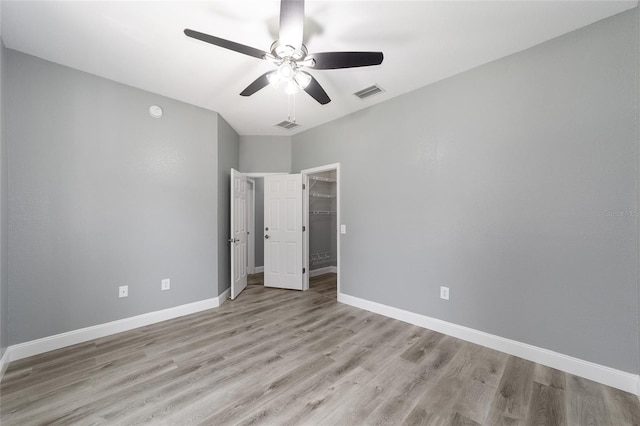 unfurnished bedroom with ceiling fan, light wood-type flooring, a spacious closet, and a closet