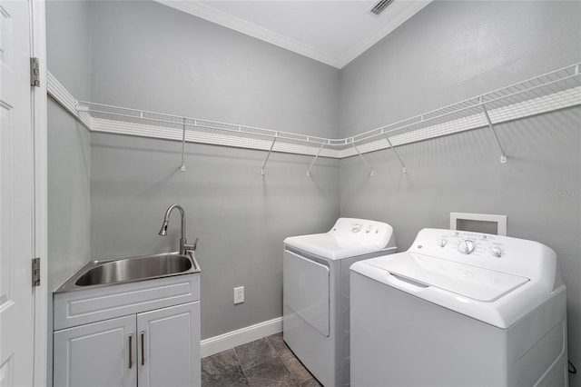 laundry area featuring washing machine and dryer, crown molding, and sink