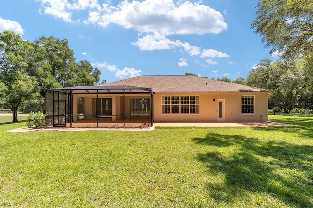 back of property featuring glass enclosure, a yard, and a patio