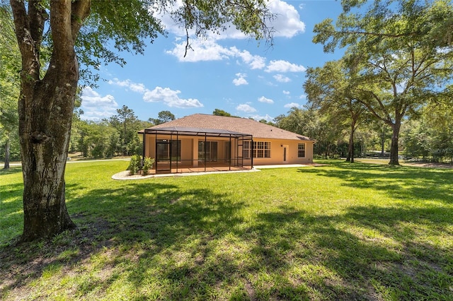 rear view of property featuring glass enclosure, a lawn, and a patio