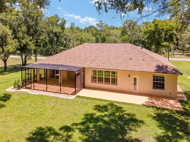 back of property featuring a shingled roof, a patio, glass enclosure, a yard, and stucco siding