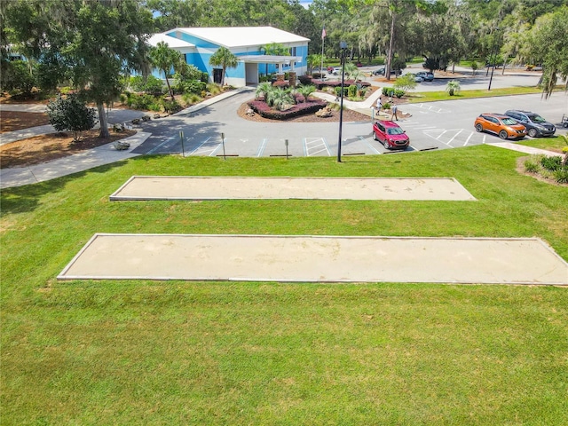 view of community featuring uncovered parking and a yard