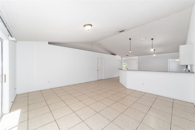 empty room with light tile patterned floors and vaulted ceiling