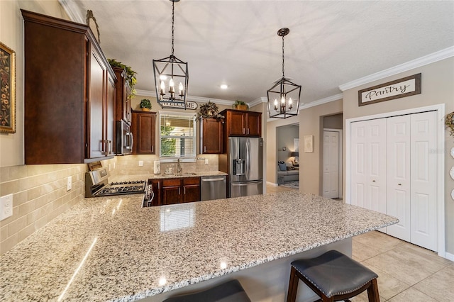 kitchen featuring decorative backsplash, kitchen peninsula, a breakfast bar, stainless steel appliances, and hanging light fixtures