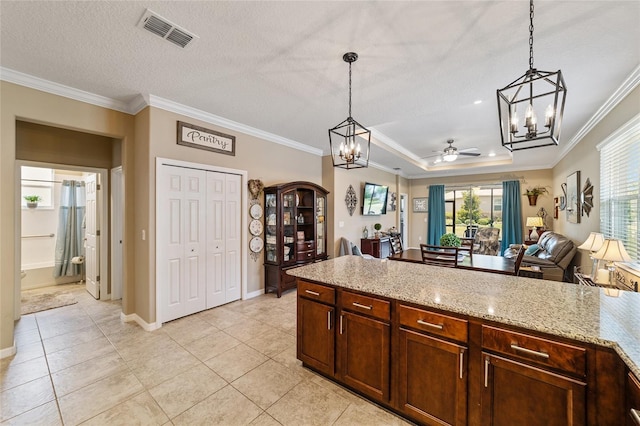 kitchen featuring light stone countertops, decorative light fixtures, ceiling fan, and ornamental molding